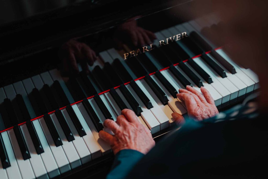 A close up of senior hands playing a grand piano
