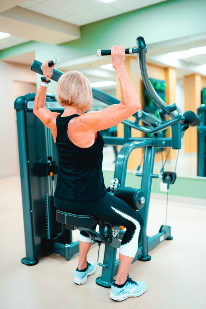A senior woman uses a gym machine