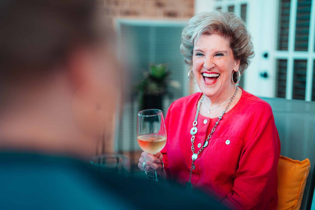 A senior woman enjoys time with friends and a glass of wine