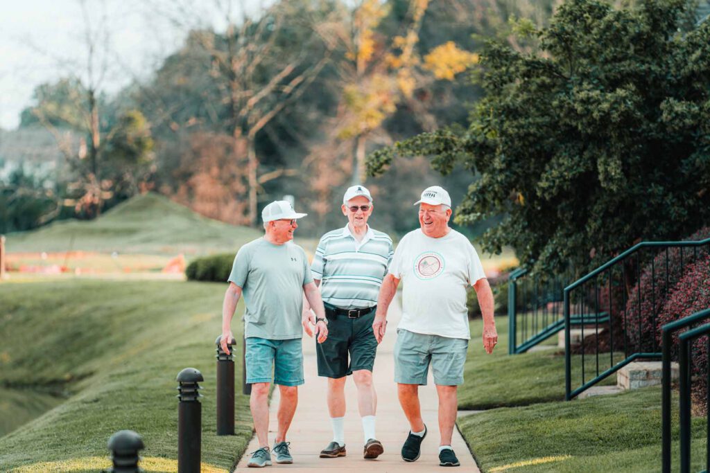 Three senior men on a walk down a well-manicured neighborhood sidewalk