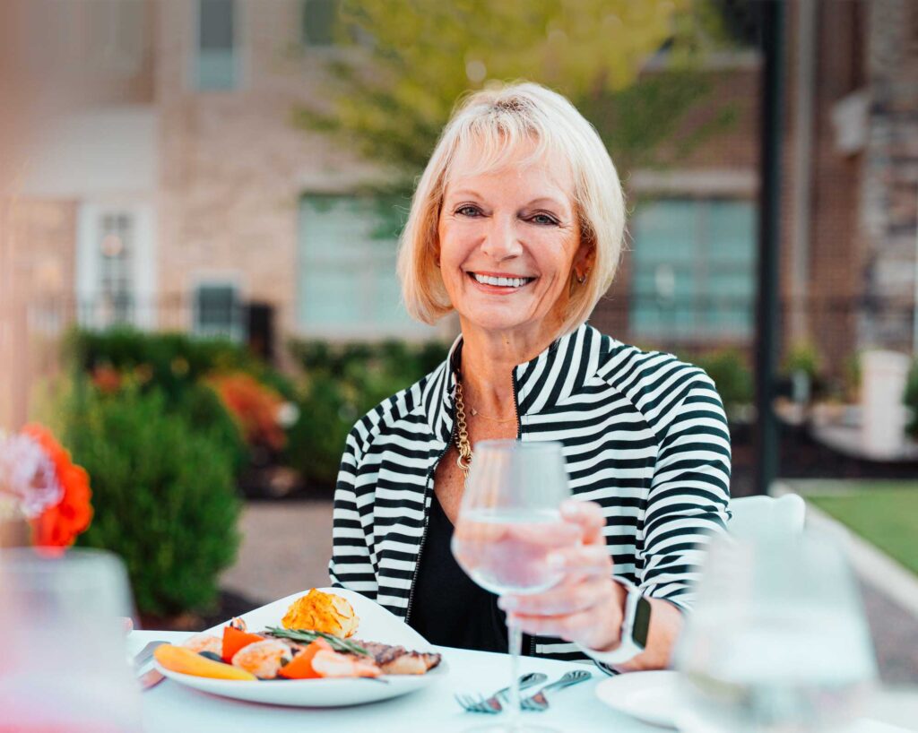 Senior woman dines outdoors in the courtyard at The Farm at Bailey Station